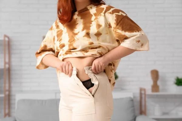 Image of woman trying to do her trousers up after pregnancy weight gain Chapeltown
