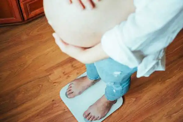 Image of woman weighing herself and experiencing weight gain through pregnancy Chapeltown